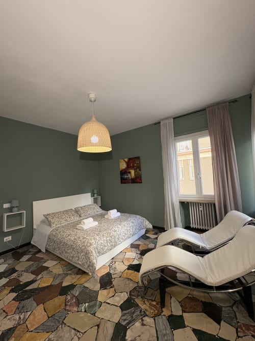 Camera Aida di Le Arche hotel a Verona con letto matrimoniale, lampada a sospensione, pareti verdi e pavimento in pietra