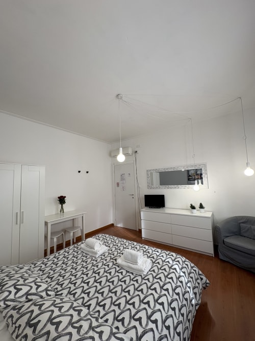 Camera moderna dell'hotel Le Arche a Verona con letto decorato, mobili bianchi, lampade a sospensione e specchio a parete