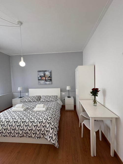 Camera moderna dell'hotel Le Arche a Verona con mobili bianchi, biancheria a motivi, pavimenti in legno e arredamento contemporaneo