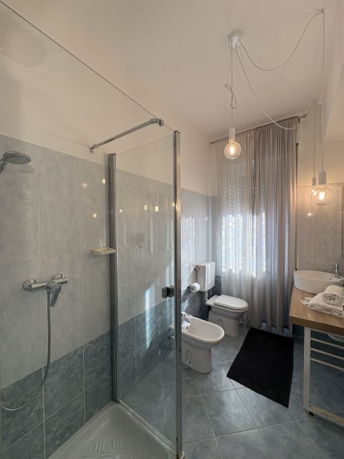 Bagno moderno dell'hotel Le Arche Verona con doccia walk-in, doppio lavabo e illuminazione a sospensione