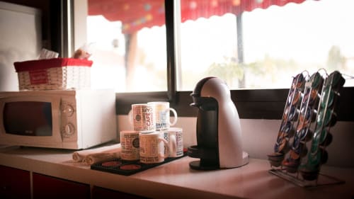 Encimera de cocina en apartamento de Mérida con cafetera, tazas y reloj cerca de ventanas soleadas