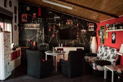 Elegante sala de estar en Mérida con paredes rojas, muro de mármol negro, área de entretenimiento y decoración ecléctica.