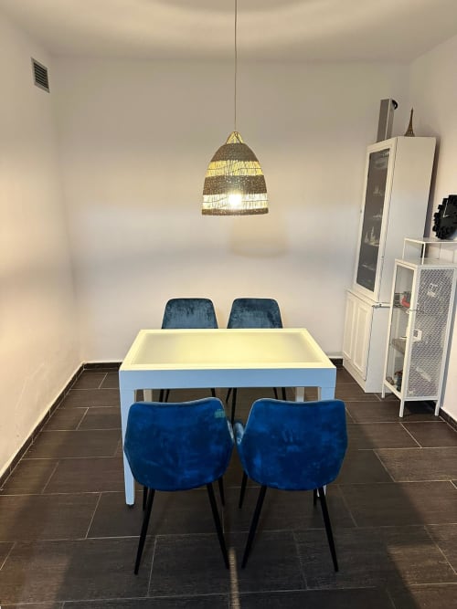 Comedor moderno con sillas de terciopelo azul, mesa blanca y lámpara colgante de fibra tejida en Mérida