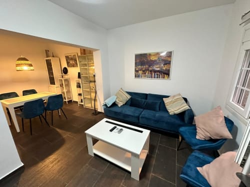 Apartamento moderno en Mérida con sofá azul, comedor y obra de arte con vista a la ciudad