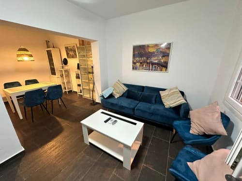 Sala de estar moderna en Mérida con sofá azul, mesa de comedor y cuadros con vistas a la ciudad en las paredes