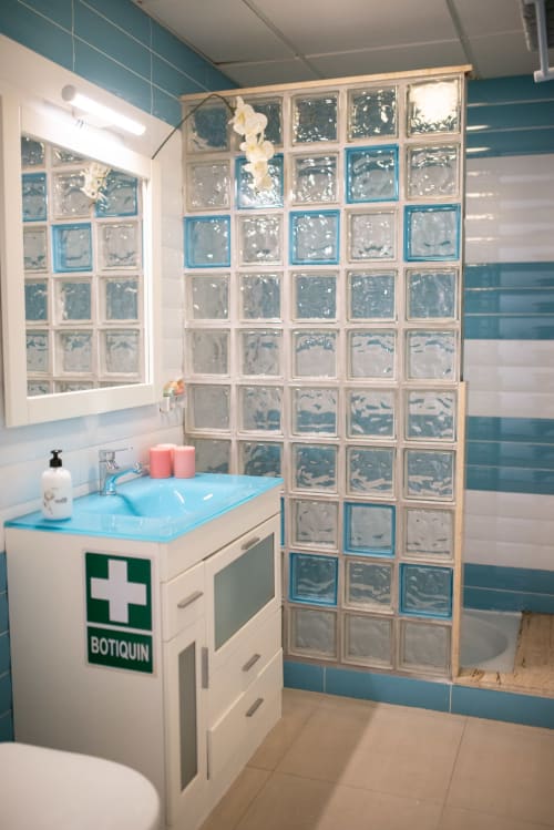 Cuarto de baño moderno con detalles en azul, pared de ducha de bloques de vidrio y tocador en el apartamento Gestyp-AT de Mérida, España