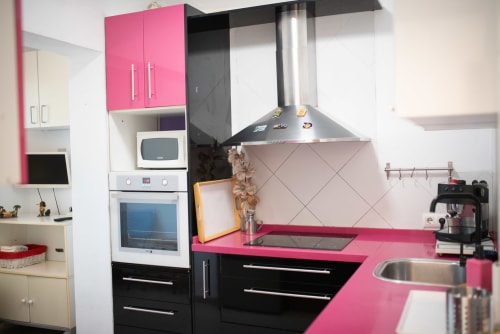 Cocina moderna en rosa y negro del apartamento Gestyp-AT en Mérida con campana extractora de acero inoxidable y encimeras de granito
