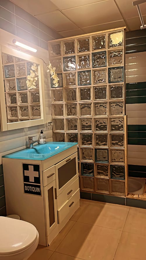 Baño moderno con lavabo turquesa, mampara de ducha de bloques de vidrio y azulejos decorativos en el departamento Gestyp-AT de Mérida