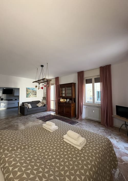 Spaziosa camera da letto con letto matrimoniale, zona living, divano e mobili in legno a Le Arche Verona