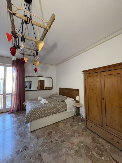 Camera luminosa presso l'appartamento Le Arche Verona con letto in legno, armadio, mobile decorativo da soffitto e pavimentazione in marmo