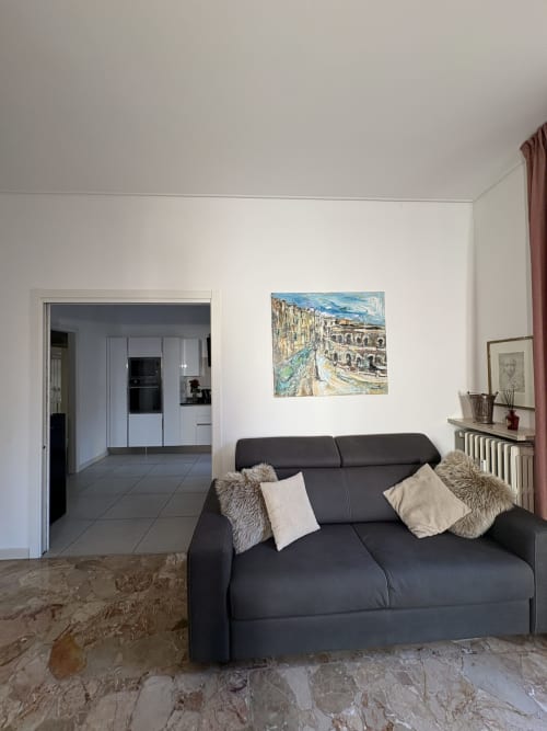 Elegante soggiorno moderno con divano scuro, pareti bianche e accesso alla cucina presso Le Arche a Verona