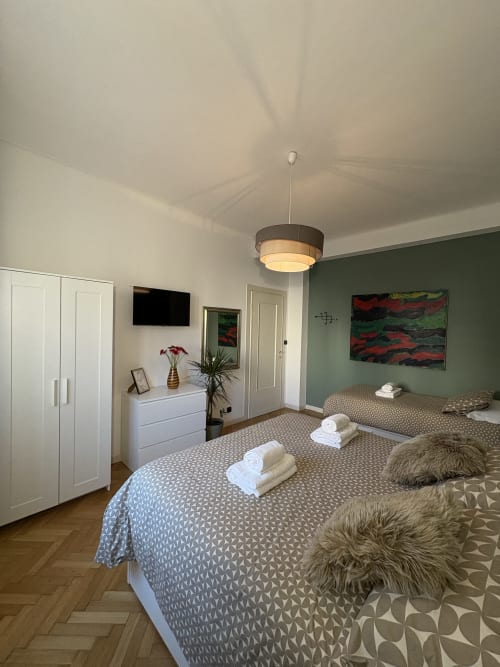 Ampia camera doppia presso l'hotel Le Arche di Verona con arredi moderni, parete accent verde e illuminazione contemporanea.