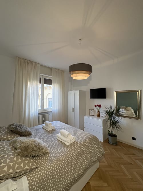 Camera moderna all'hotel Le Arche di Verona con letto matrimoniale, arredi bianchi, luci sospese e design contemporaneo