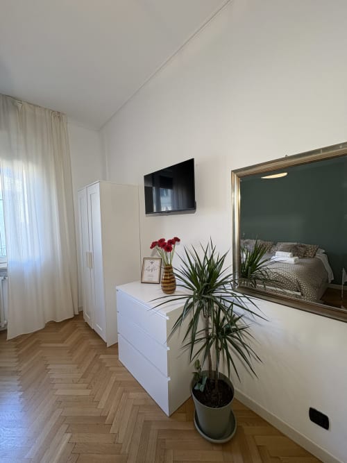 Camera moderna all'hotel Le Arche di Verona con arredi bianchi, TV a schermo piatto, grande specchio e piante in vaso