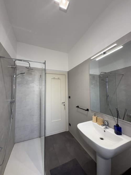 Bagno moderno nella camera Catullo 12 dell'hotel Le Arche a Verona, con doccia, lavabo e specchio con illuminazione.
