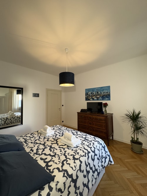 Camera moderna all'hotel Le Arche di Verona con biancheria decorativa, mobili in legno e illuminazione a sospensione