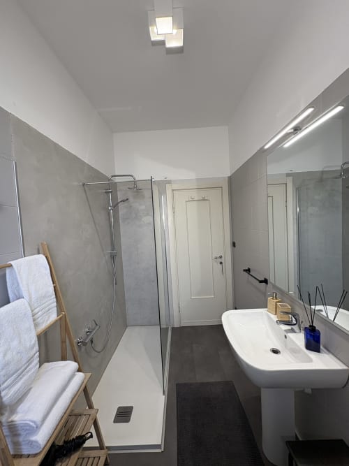 Bagno moderno dell'hotel di Verona con doccia walk-in, lavabo su piedistallo, scaldasalviette e illuminazione dello specchio