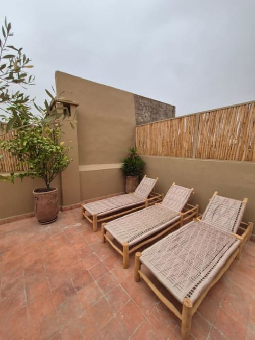 Chaises longues du Riad Casa Angelo sur la terrasse avec plante en pot d'argile, Marrakech