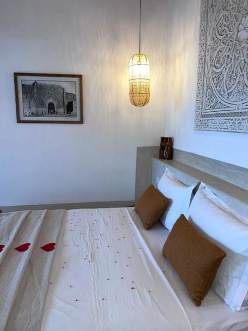 Chambre Hana Suite du Riad Casa Angelo à Marrakech avec lit, coussins, luminaire suspendu et décoration murale marocaine