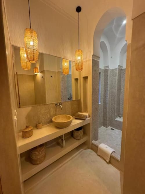 Salle de bains moderne au Riad Casa Angelo, Marrakech avec luminaires en osier tressé, vasque en pierre et douche carrelée