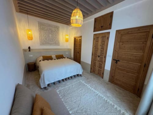 Suite Hana du Riad Casa Angelo à Marrakech avec portes sculptées traditionnelles, luminaires suspendus et patio intérieur