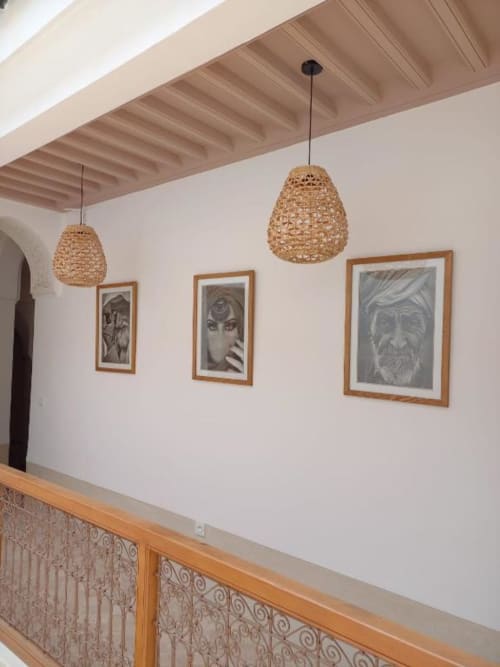 Mezzanine du Riad Casa Angelo avec suspensions en fibres tressées, poutres en bois, portraits encadrés et balustrade en métal ouvragé