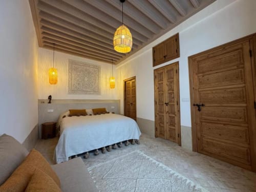 La Suite Hana du Riad Casa Angelo à Marrakech avec lit, suspensions dorées, portes en bois travaillé et carrelage