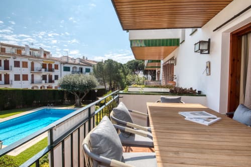 Terrassa de l'Apartment Ancora amb vistes a la piscina compartida a Palafrugell, amb zona de descans i sòl de fusta modern