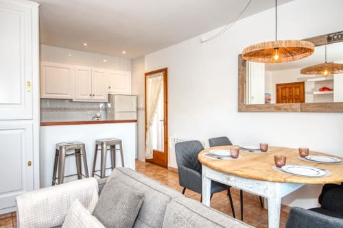 Menjador d'apartament modern amb taula de fusta, cuina i barra al centre de Palafrugell