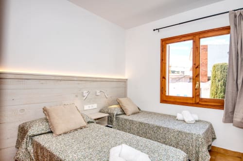 Dormitori doble de l'apartament Ancora a Palafrugell amb finestres de fusta, vista a la terrassa i equipaments moderns