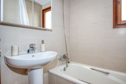 Bany modern amb lavabo blanc corbat, armari mirall i banyera a l'Ap. Ancora de Finques Garcia Enrich