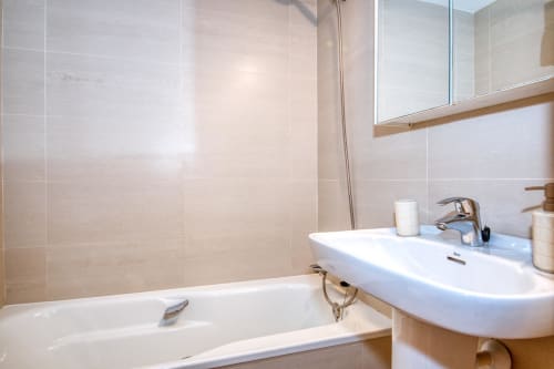 Bany modern de l'Ap. Ancora a Palafrugell amb lavabo blanc, banyera i parets amb rajoles