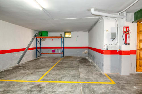 Aparcament subterrani de l'apartament Finques Garcia Enrich a Palafrugell amb places marcades i estanteries d'emmagatzematge