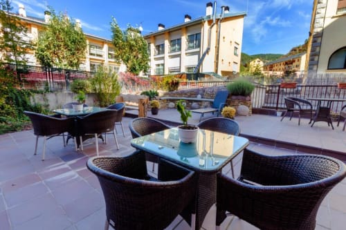 Outdoor terrace at Hotel Flor de Neu in El Pont de Suert with wicker seating, glass tables, and mountain views