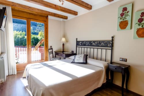 Chambre d'hôtel lumineuse avec poutres en bois, vue montagne et décor traditionnel à Flor de Neu, El Pont de Suert