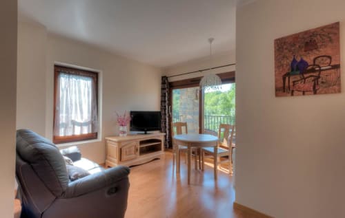 Salon moderne d'appartement avec fauteuil inclinable, TV, table à manger et vue sur balcon à l'Hôtel Flor de Neu, El Pont de Suert