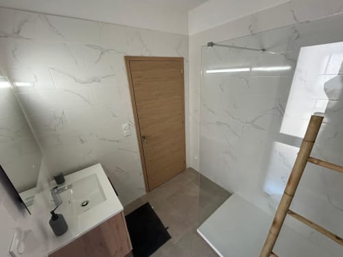 Modern bathroom in Villa Corail with marble-effect tiles, wooden door, and walk-in shower, managed by Corsu di Core
