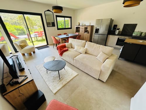 Modern open-plan living area in Villa Corail, with cream sofa, dining table, equipped kitchen, managed by Corsu di Core