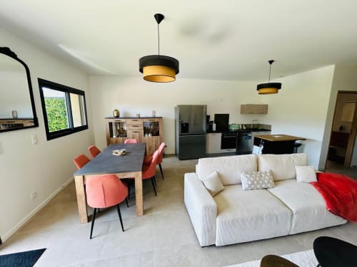 Modern open-plan living area of Villa Corail  featuring cream sofa, dining table with red chairs, managed by Corsu di Core