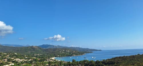 Panoramic sea view of Favone coast with turquoise bay, anchored sailboats, and forested mountains in Corsica, managed by Corsu di Core