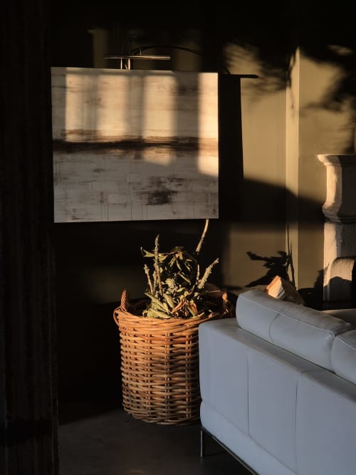 Sunlit hotel room corner at Moulin Renaudiots with wicker plant basket and white cushioned furniture