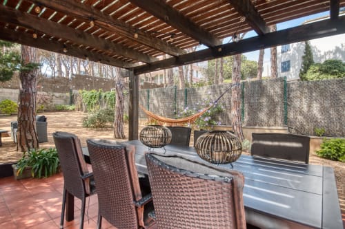 Shaded patio with wicker chairs, dining table, and hammock at Finques Garcia Enrich apartment in Palafrugell
