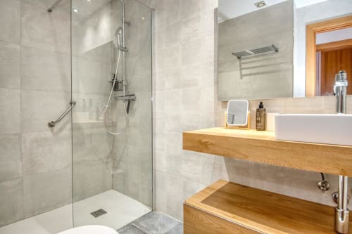 Modern bathroom with walk-in shower, wooden vanity, and white vessel sink in Brisa de Calella apartment, Palafrugell