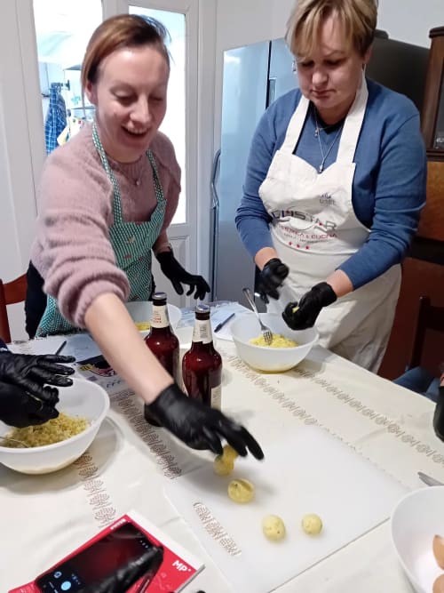 Due donne preparano la pasta durante un corso di cucina a Tales of Abruzzo ad Atessa, Italia, indossando grembiuli e guanti neri