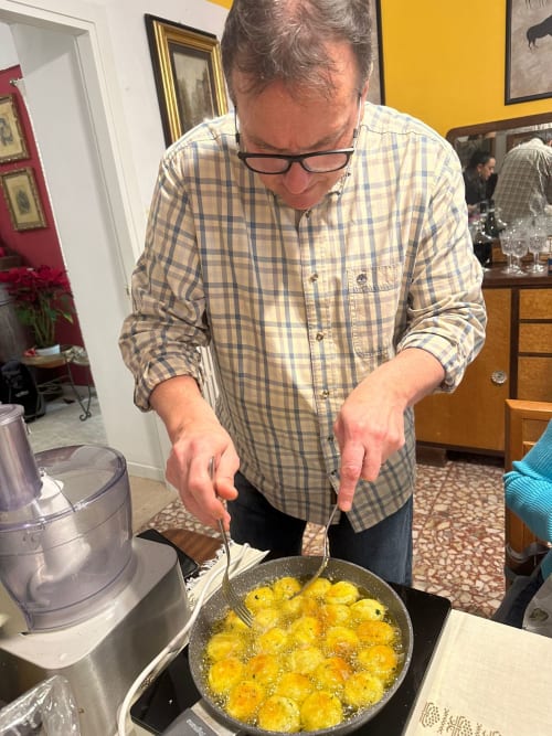 Uomo che cucina polpette dorate in padella presso l'hotel Tales of Abruzzo ad Atessa, Italia