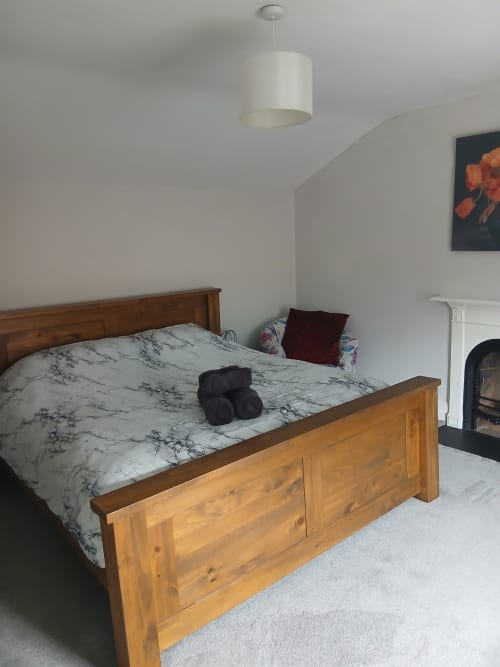 Spacious Super King bedroom at Eglinton Road Bray with wooden bed, marble bedding, pendant light, and fireplace in Bray,