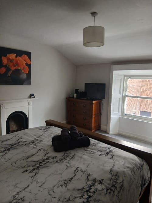 Modern Super King bedroom at Eglinton Road Bray with marble bedding, fireplace, TV, and patio doors overlooking brick