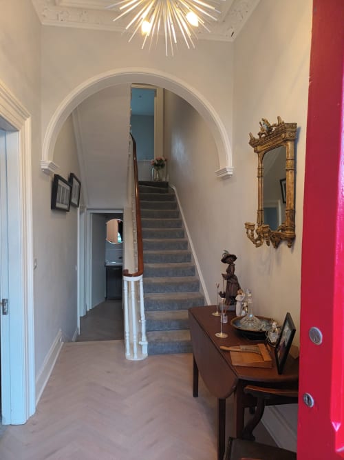 Elegant hallway at Eglinton Road Bray with grand archway, staircase, and period furnishings including gilt mirror and wooden