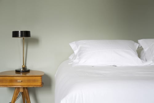 Chambre moderne du gîte Mas De Lafeuillade à Montpellier avec literie blanche et lampe de chevet en bois