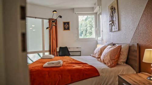 Chambre terracotta de la Villa Pré d'Oro avec lit double, couvre-lit orange et vue sur jardin
